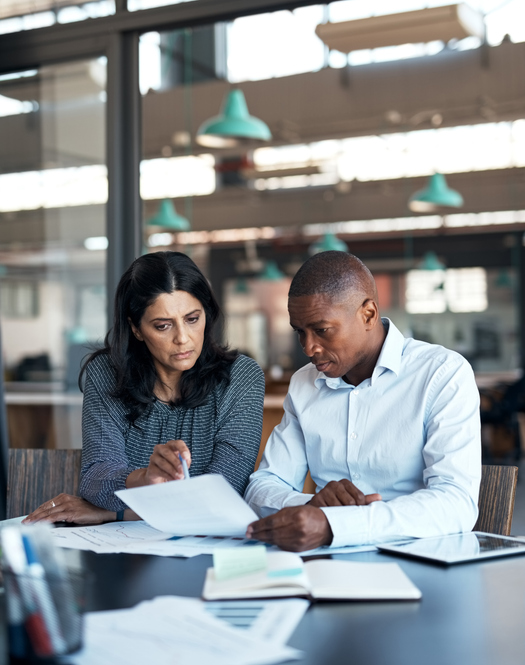 Shot of a businessman and businesswoman going over paperwork in a modern office